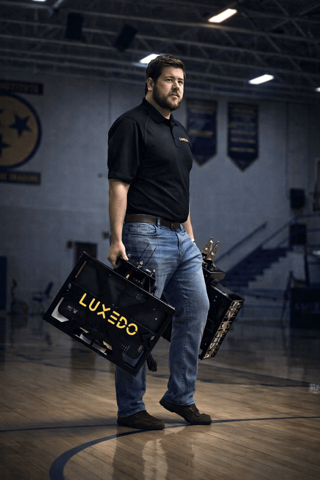 Luxedo installer carrying projection equipment into a school gymnasium
